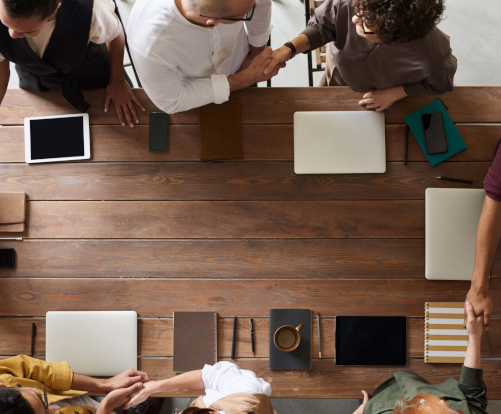 Mesa con gente de pie saludándose alrededor de la mesa