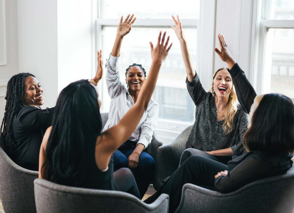 Reunión de chicas levantando todas la mano respondiendo a una pregunta