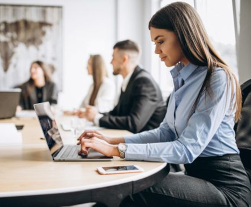 Ejecutiva trabajando con su portátil en mesa de trabajo.